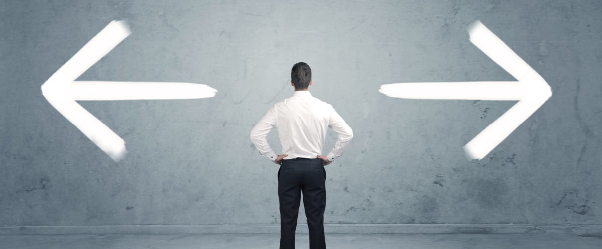 Mann steht zwischen zwei Pfeilen
