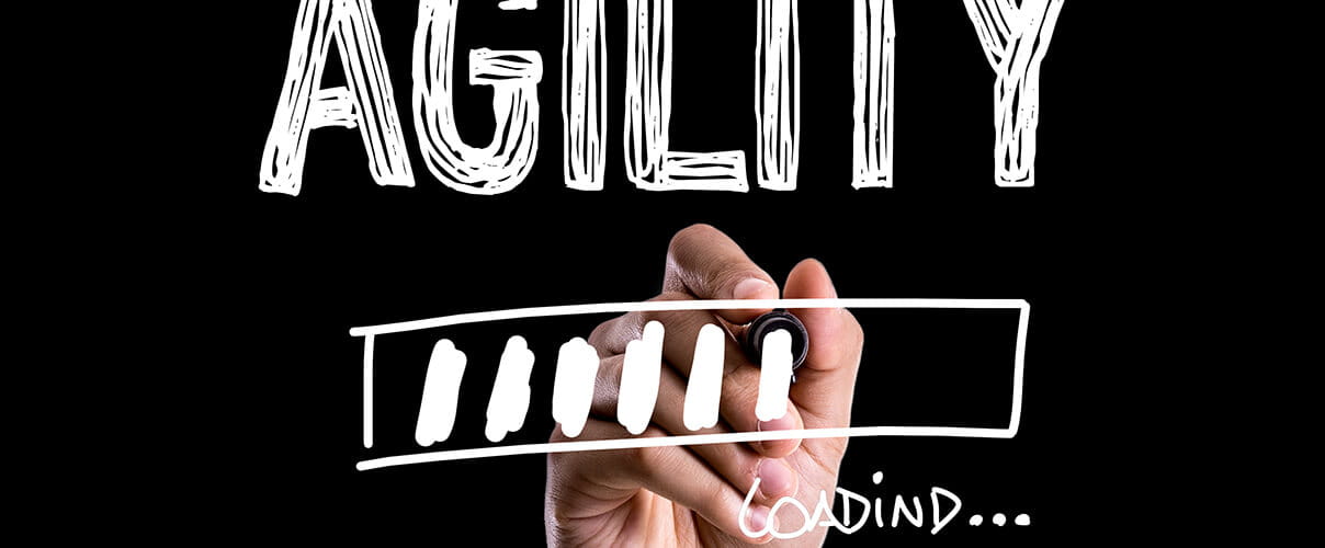 Hand schreibt Wort "Agility" auf Wandtafel