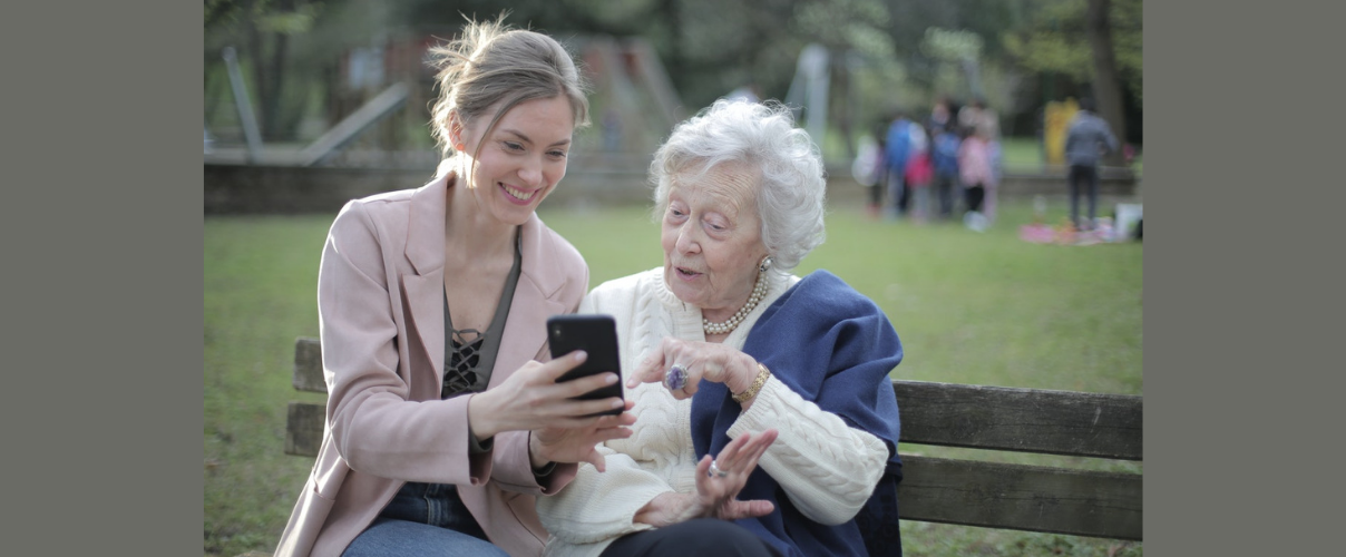 Junge Frau erklärt älterer Frau Funktionen auf dem Smartphone