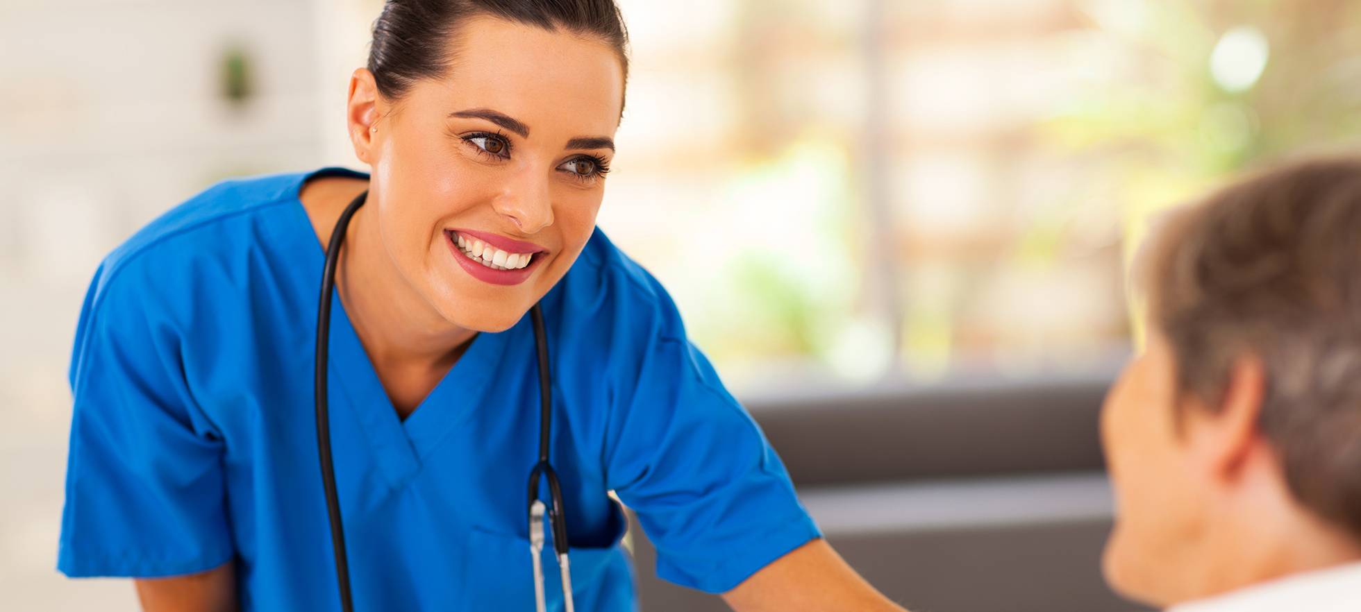 Pflegefachperson kümmert sich um ältere Patientin im Gespräch