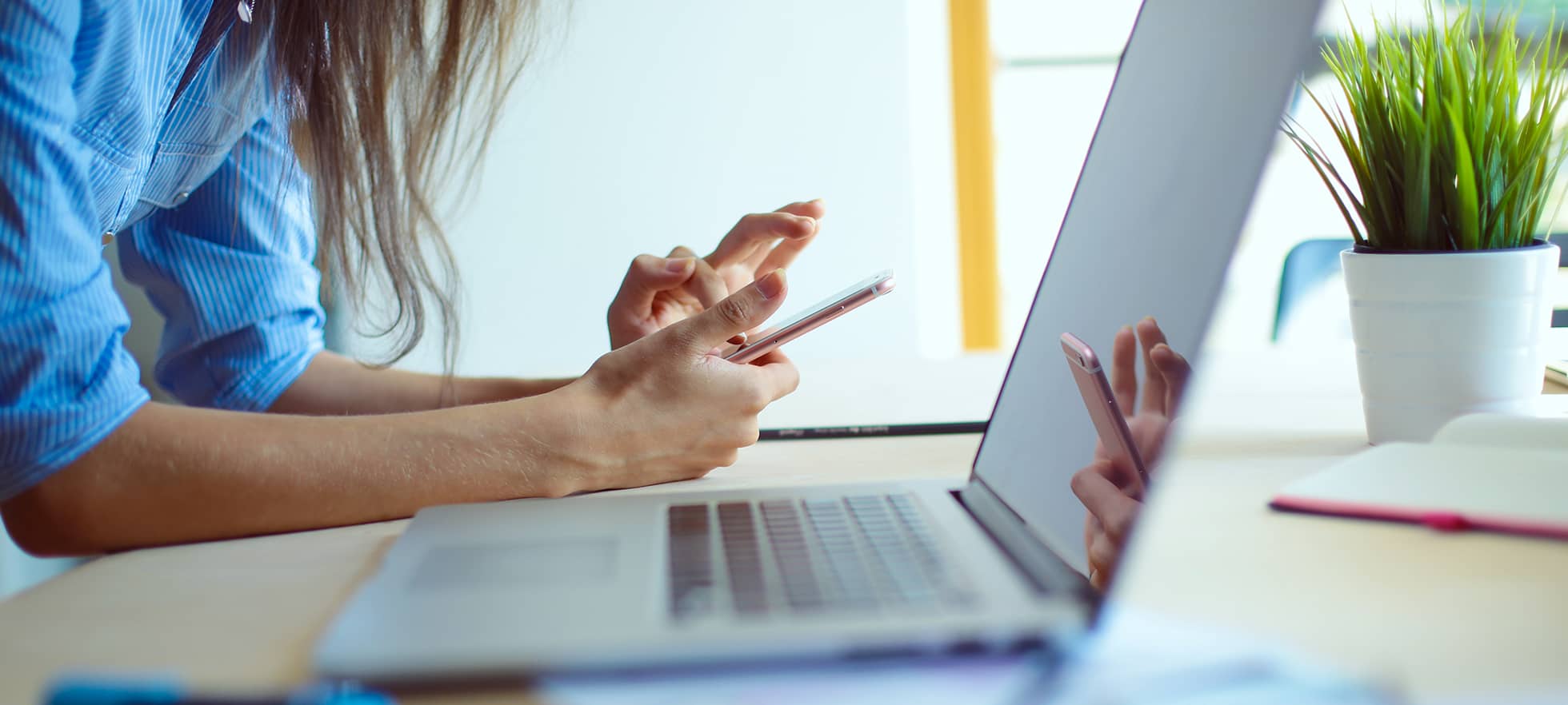 Frau am Laptop mit Smartphone