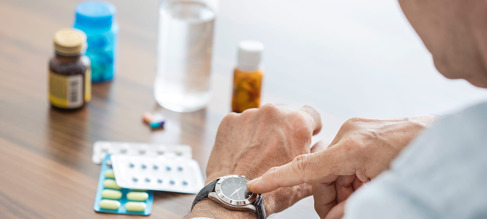 Mann nimmt Medikamente und schaut auf Uhr