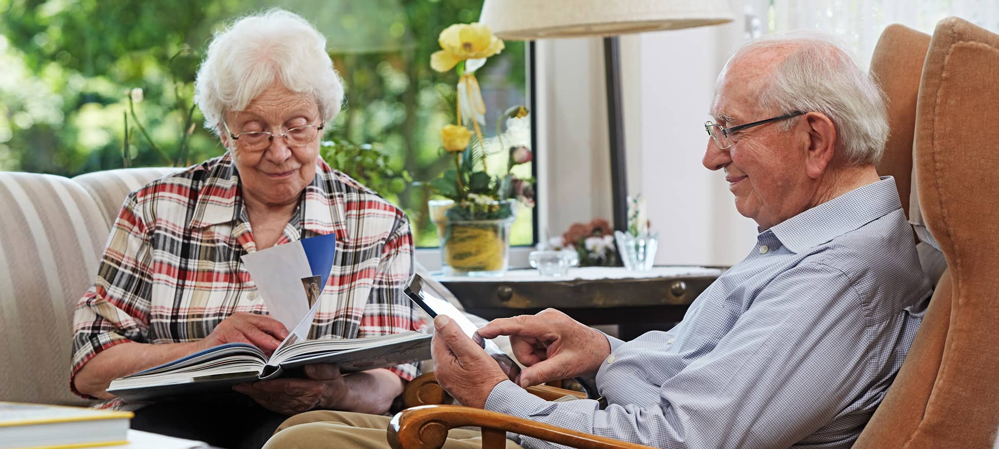 Zwei ältere Personen sitzen im Wohnzimmer und lesen