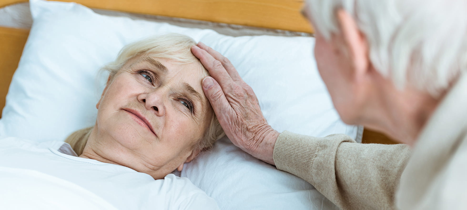 Frau pflegt andere Rentnerin am Krankenbett