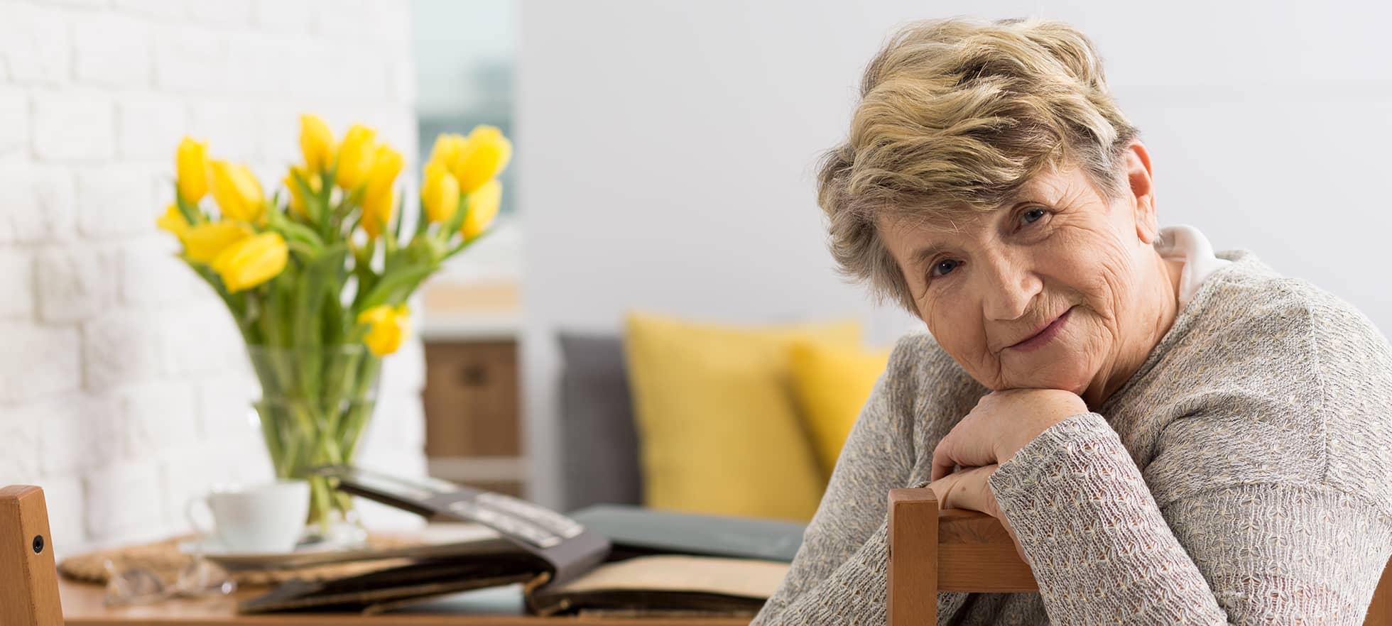 Alte Frau am Stubentisch mit Blumen