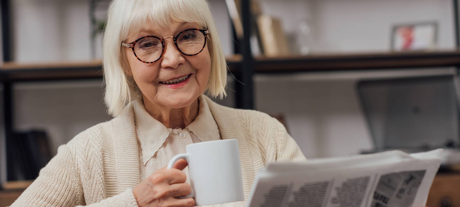 Aeltere Frau mit Kaffee und Zeitung