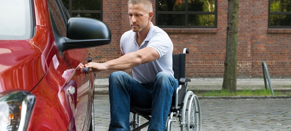 Mann im Rollstuhl steigt selbstständig ins Auto