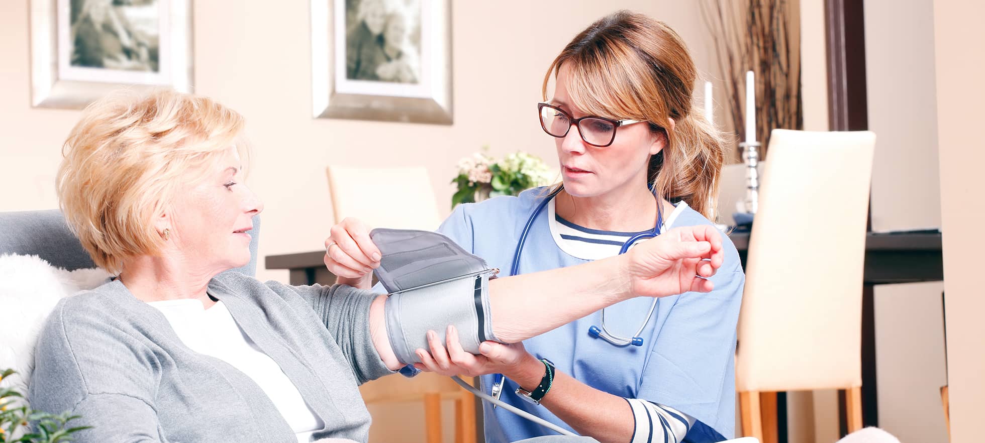 Pflegerin pflegt aeltere Frau zu Hause, Blutdruckmessen
