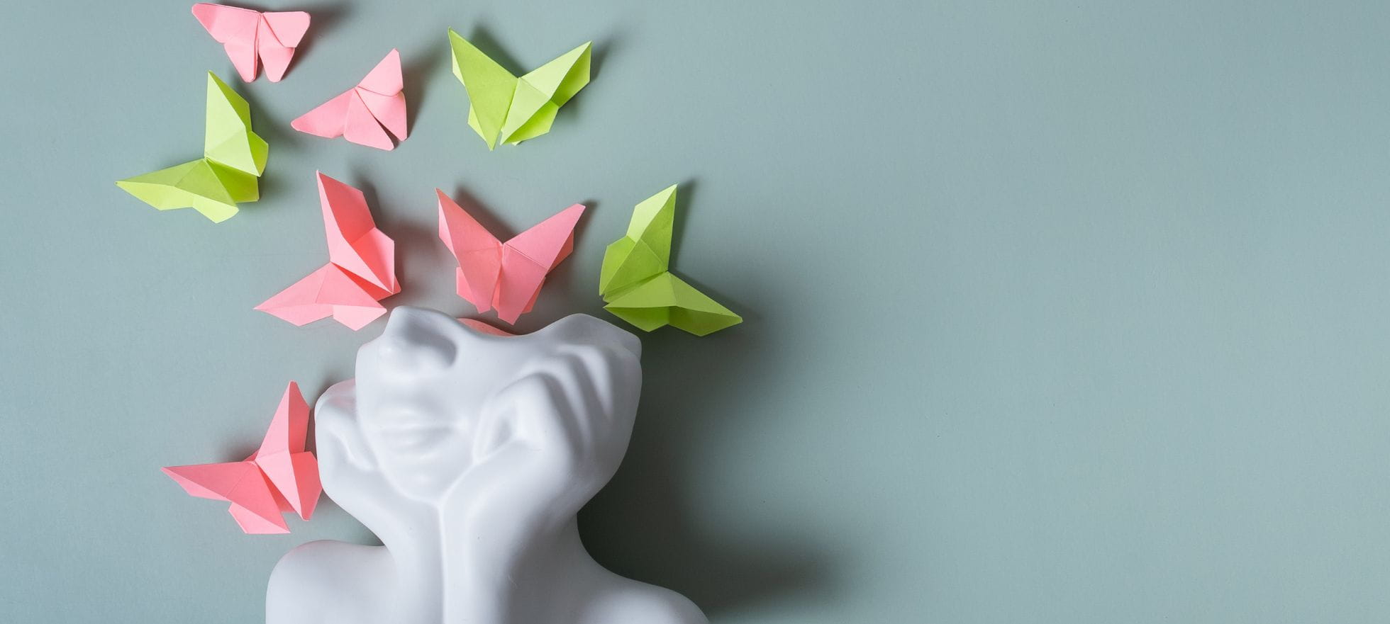 Weisse Skulptur mit Origami-Schmetterlingen, die aus dem Kopf aufsteigen.