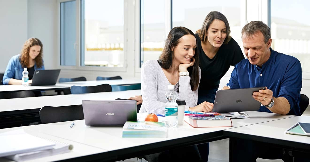 Drei Personen schauen auf Laptop