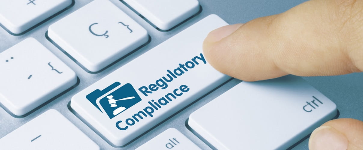 Finger auf Taste mit Aufschrift Regulatory Compliance Finger auf Taste mit Aufschrift Regulatory Compliance